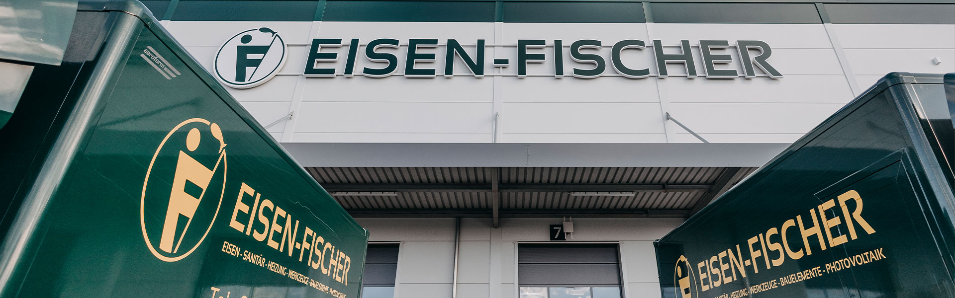 Firmengebäude von Eisen-Fischer mit sichtbarem Logo und Fuhrpark im Vordergrund.